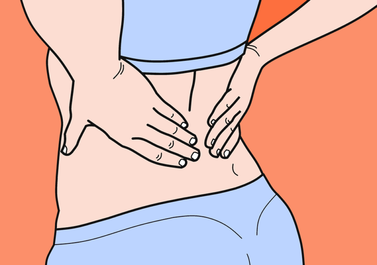 A woman rubs her lower back to show she's feeling pain